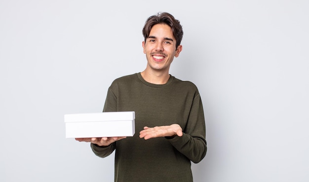 Junger hispanischer Mann, der fröhlich lächelt, sich glücklich fühlt und ein Konzept zeigt. White-Box-Konzept