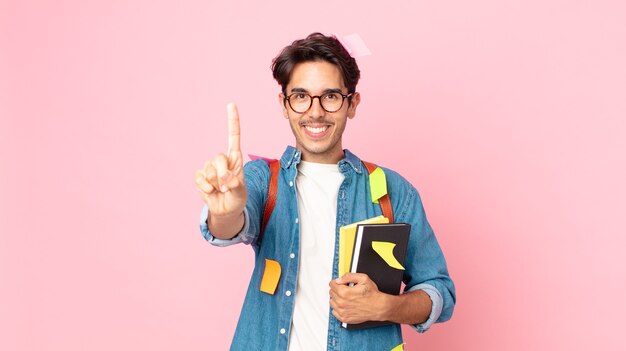 junger hispanischer mann, der lächelt und freundlich aussieht und nummer eins zeigt. studentisches Konzept