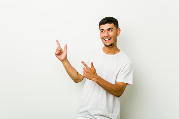 Junger hispanischer Mann, der mit dem Zeigefinger-Kopienraum, Aufregung und Wunsch ausdrückend zeigt.