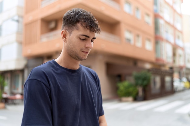 Junger hispanischer Mann, der mit ernster Miene auf der Straße zur Seite schaut
