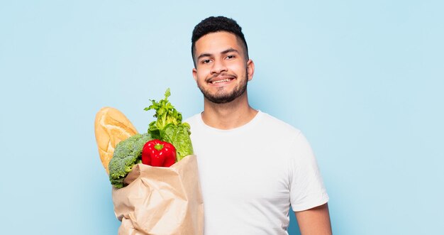 junger hispanischer mann glücklicher ausdruck. Einkaufsgemüse-Konzept