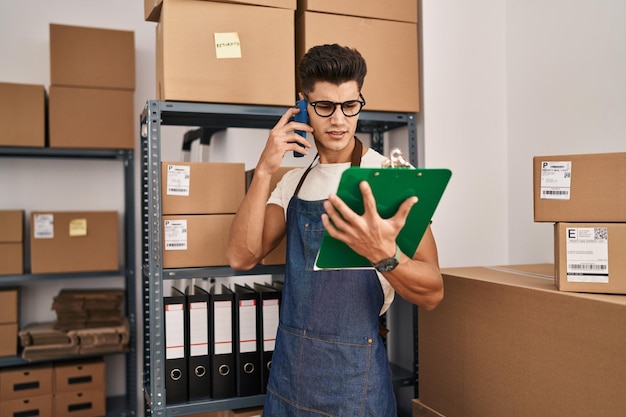 Foto junger hispanischer mann im e-commerce-geschäft, der im büro auf dem smartphone spricht