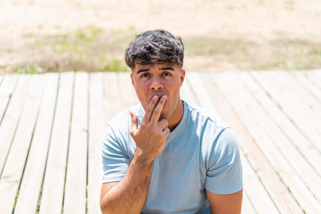 Foto junger hispanischer mann im freien überrascht und schockiert, während er nach rechts blickt