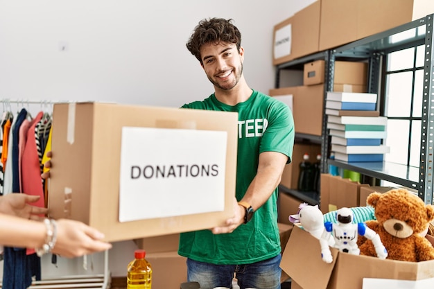 Junger hispanischer Mann in freiwilliger Uniform, der Spendenbox im Wohltätigkeitszentrum gibt