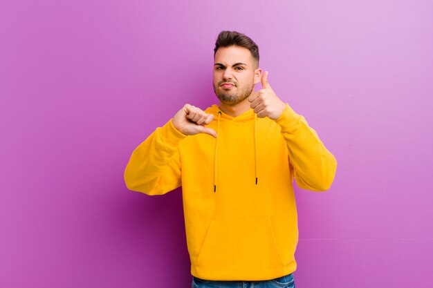 Junger hispanischer Mann mit lässigem Blick gegen lila Wand