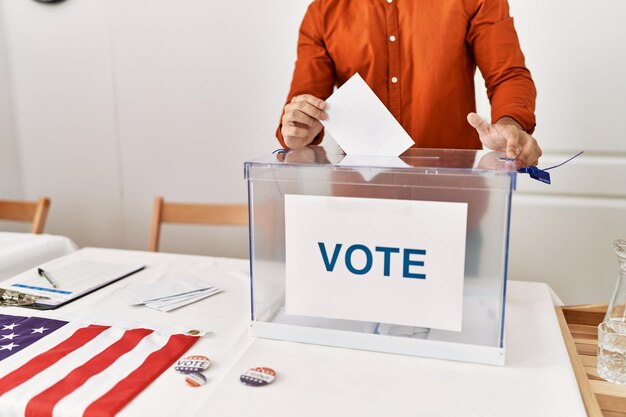 Junger hispanischer Mann wirft seine Stimme in die Wahlurne des Wahlkollegiums