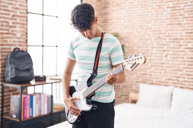 Junger hispanischer Teenager-Musiker spielt E-Gitarre im Schlafzimmer