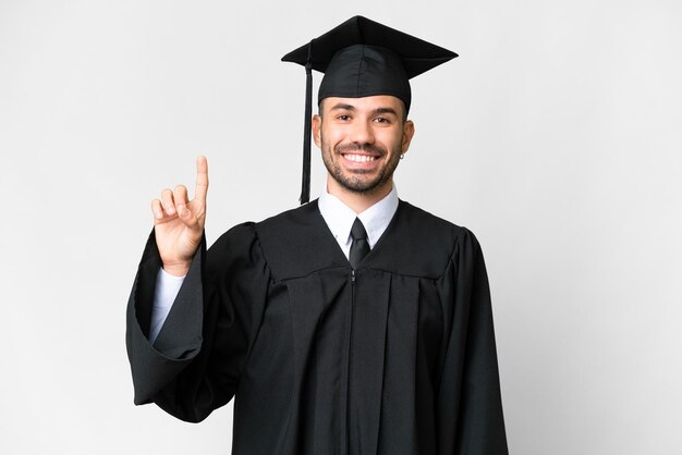 Junger Hochschulabsolvent über isoliertem weißem Hintergrund, der einen Finger im Zeichen der Besten zeigt und hebt