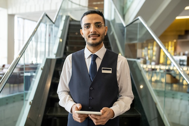 Junger Hotelmanager mit Tablet vor Rolltreppe