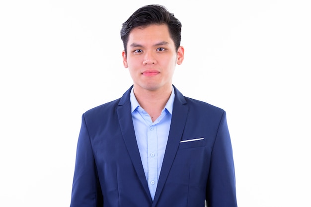 junger hübscher asiatischer Geschäftsmann, der Anzug lokalisiert gegen weiße Wand trägt