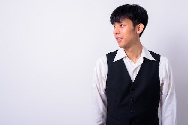 junger hübscher asiatischer Geschäftsmann gegen weiße Wand