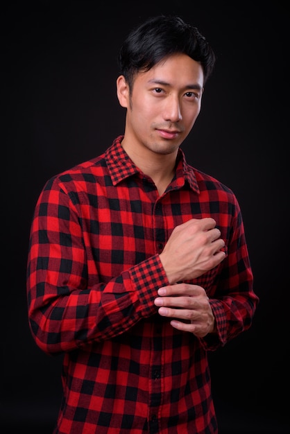 Junger hübscher asiatischer Mann auf schwarzer Wand