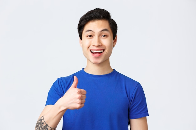 Junger hübscher asiatischer Mann, der ein blaues T-Shirt trägt