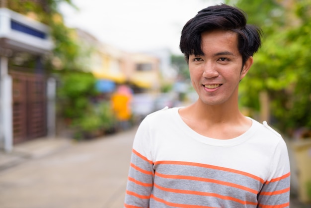 Junger hübscher asiatischer Mann in den Straßen draußen