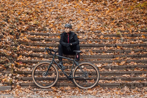 Junger hübscher athletischer Mann, der mit Fahrrad im Herbstpark steht