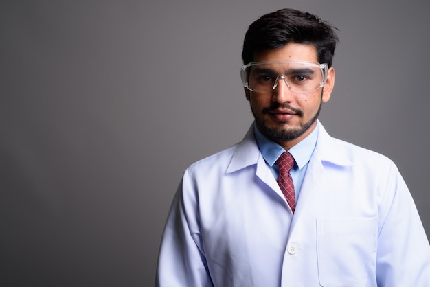 junger hübscher bärtiger persischer Mannarzt, der Schutzbrille trägt
