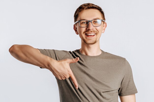 Junger hübscher Brunetmann mit Bart, der Brille trägt, zeigt Daumen nach unten