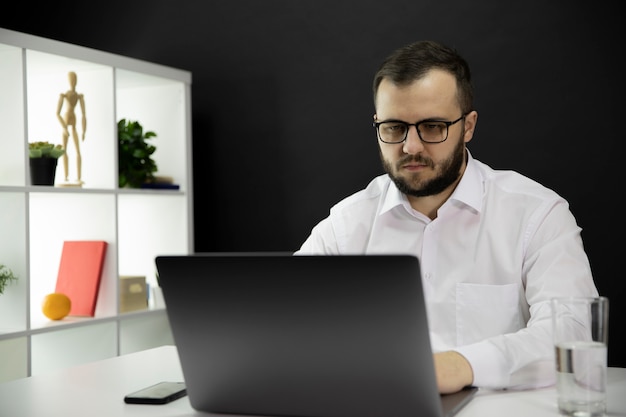 Junger hübscher Geschäftsmann, der am Computer im Heimbüro arbeitet, macht Videoanruf