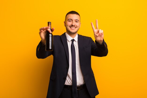 Junger hübscher Geschäftsmann gegen den flachen Hintergrund, der ein Bier isst