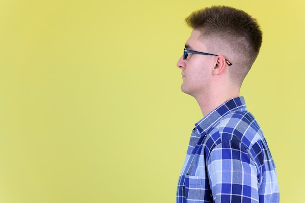 junger hübscher Hipster-Mann mit Brille gegen farbige Wand