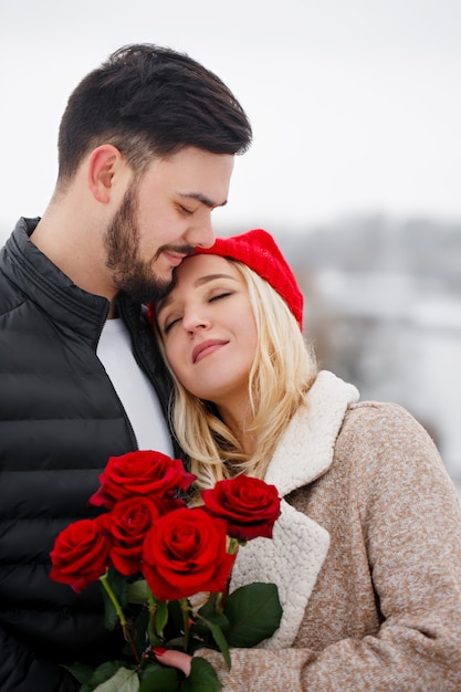 Junger hübscher Kerl, der einem Mädchen einen Strauß Rosen am Valentinstag gibt