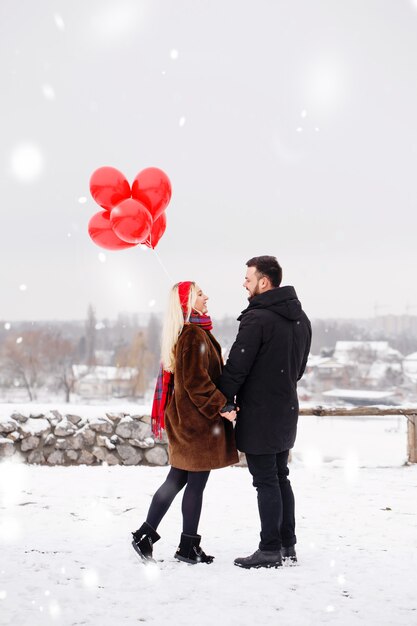 Junger hübscher Kerl und Mädchen mit Luftballons, die am Valentinstag gehen