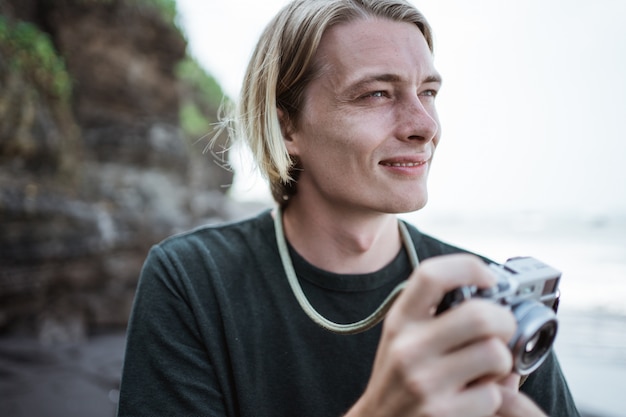 Junger hübscher männlicher Fotograf am Strand