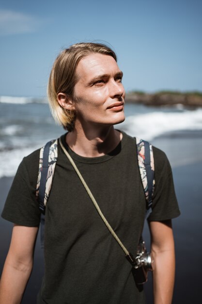 Junger hübscher männlicher Fotograf am Strand