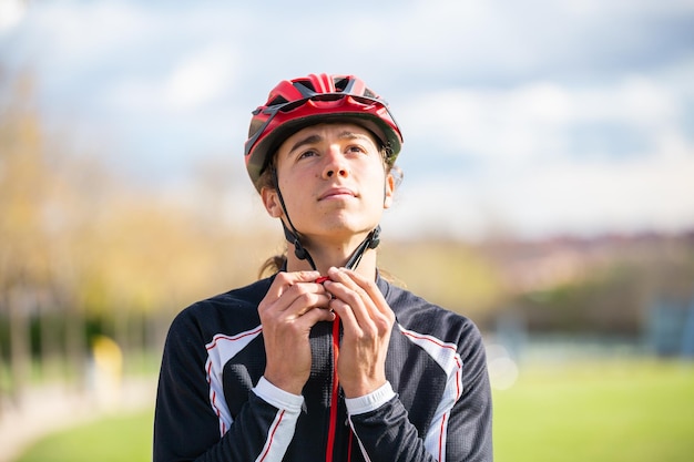 Junger hübscher männlicher Radfahrer in Sportbekleidung mit angeschnalltem Schutzhelm im wunderschönen Stadtpark