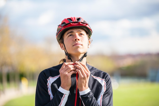 Foto junger hübscher männlicher radfahrer in sportbekleidung mit angeschnalltem schutzhelm im wunderschönen stadtpark