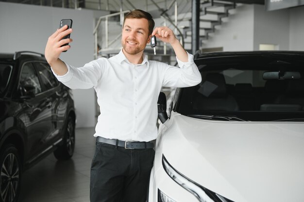 Junger hübscher Mann am Ausstellungsraum, der nahe Auto steht