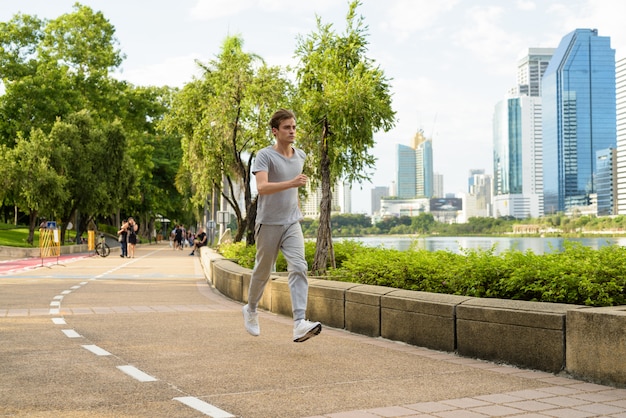 Junger hübscher Mann, der am Park joggt