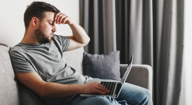 Junger hübscher Mann, der an seinem Laptop arbeitet