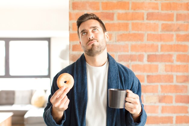 Junger hübscher Mann, der einen Kaffee zu Hause trinkt