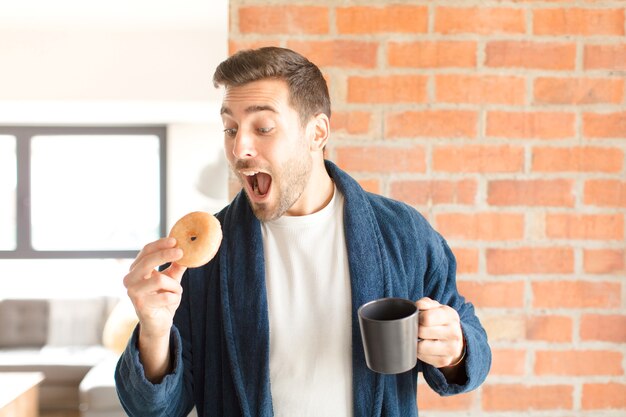 Junger hübscher Mann, der einen Kaffee zu Hause trinkt