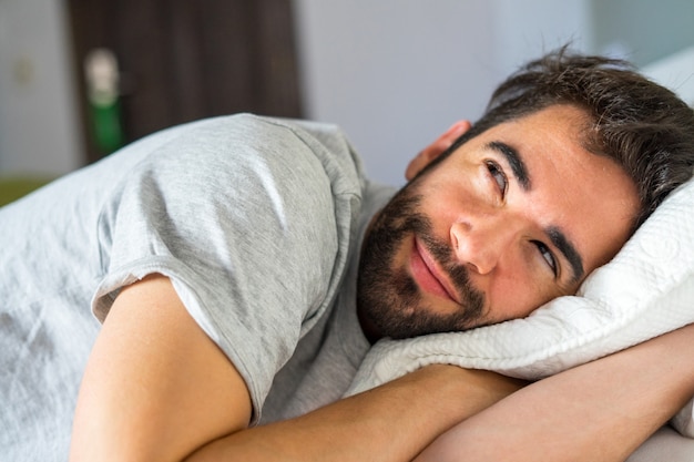 Junger hübscher Mann, der im Bett entspannt