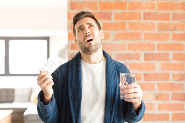 Junger hübscher Mann mit Wasser und Pillen