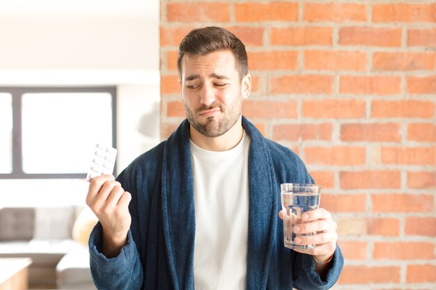 Junger hübscher Mann mit Wasser und Pillen