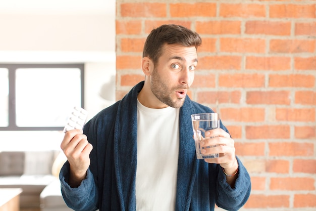 Junger hübscher Mann mit Wasser und Pillen