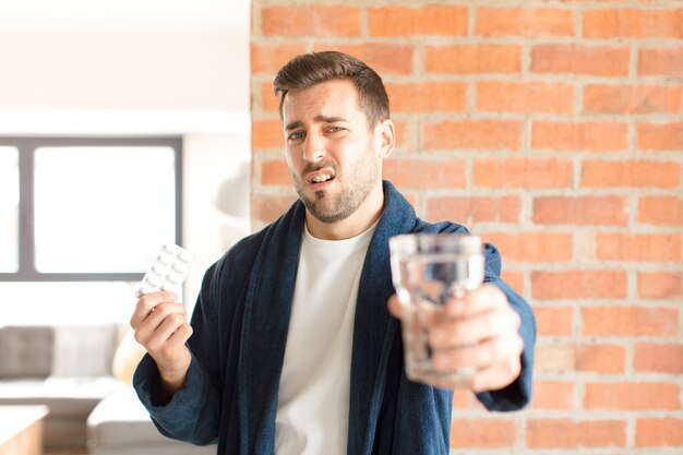 Junger hübscher Mann mit Wasser und Pillen