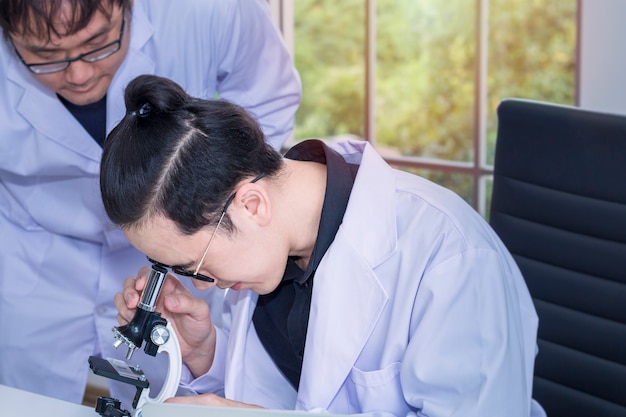 Junger hübscher Medizinstudent und wissenschaftlicher Assistent mit Mikroskopen