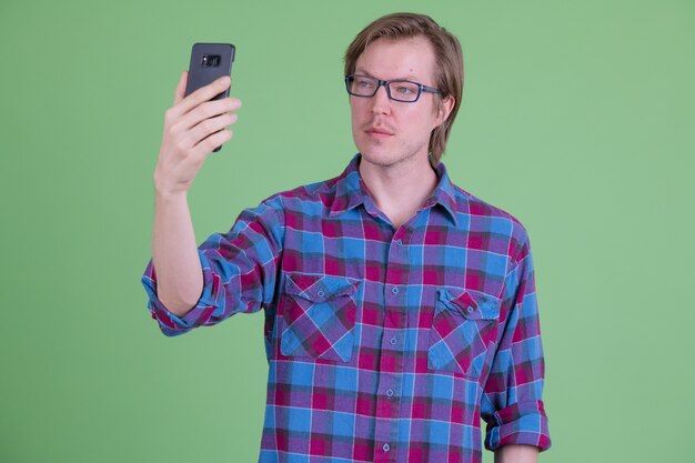 junger hübscher skandinavischer Hipster-Mann mit Brille gegen Chroma Key mit grünem Hintergrund