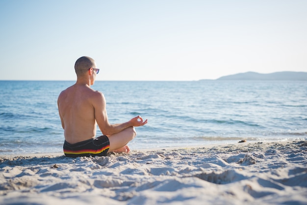 junger hübscher sportlicher Mann, der Yoga bildet