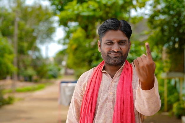 Junger indischer Bauer, der Finger nach der Abstimmung zeigt. Abstimmungszeichen in Indien