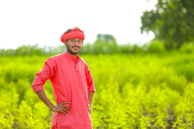 Junger indischer Bauer, der im grünen Taubenerbsenfeld steht