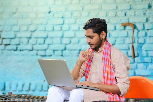 Junger indischer Bauer in Depressionen, nachdem er einige Details im Laptop gesehen hat.