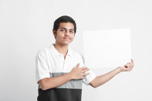 Junger indischer College-Student, der weiße Tafel auf weißer Wand zeigt