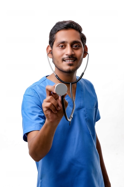 Junger indischer männlicher Doktor, der in der Hand Stethoskop auf weißem Hintergrund hält.