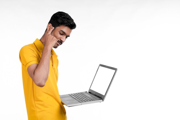 Junger indischer Mann, der Laptop auf weißem Hintergrund verwendet.