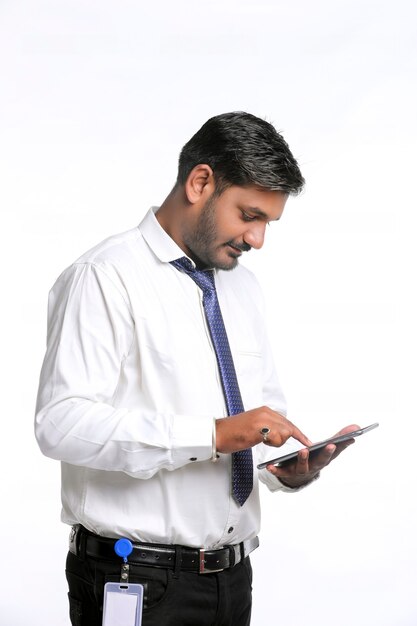 Junger indischer Mann, der Smartphone auf weißem Hintergrund verwendet.